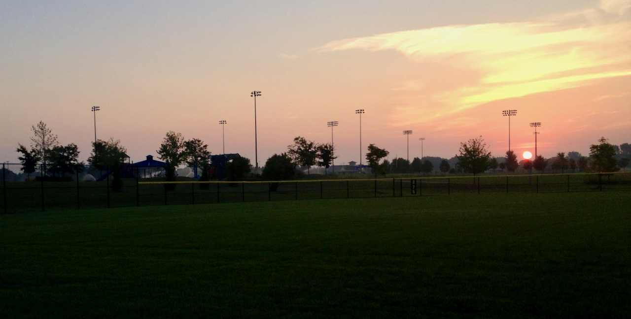 Landscape picture of a ball field as the sun rises.