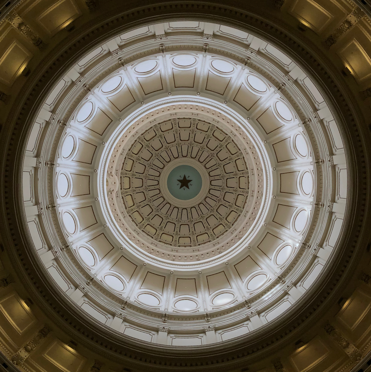 Looking up at the Texas State Capitol rotunda there is a star with the word Texas around it.