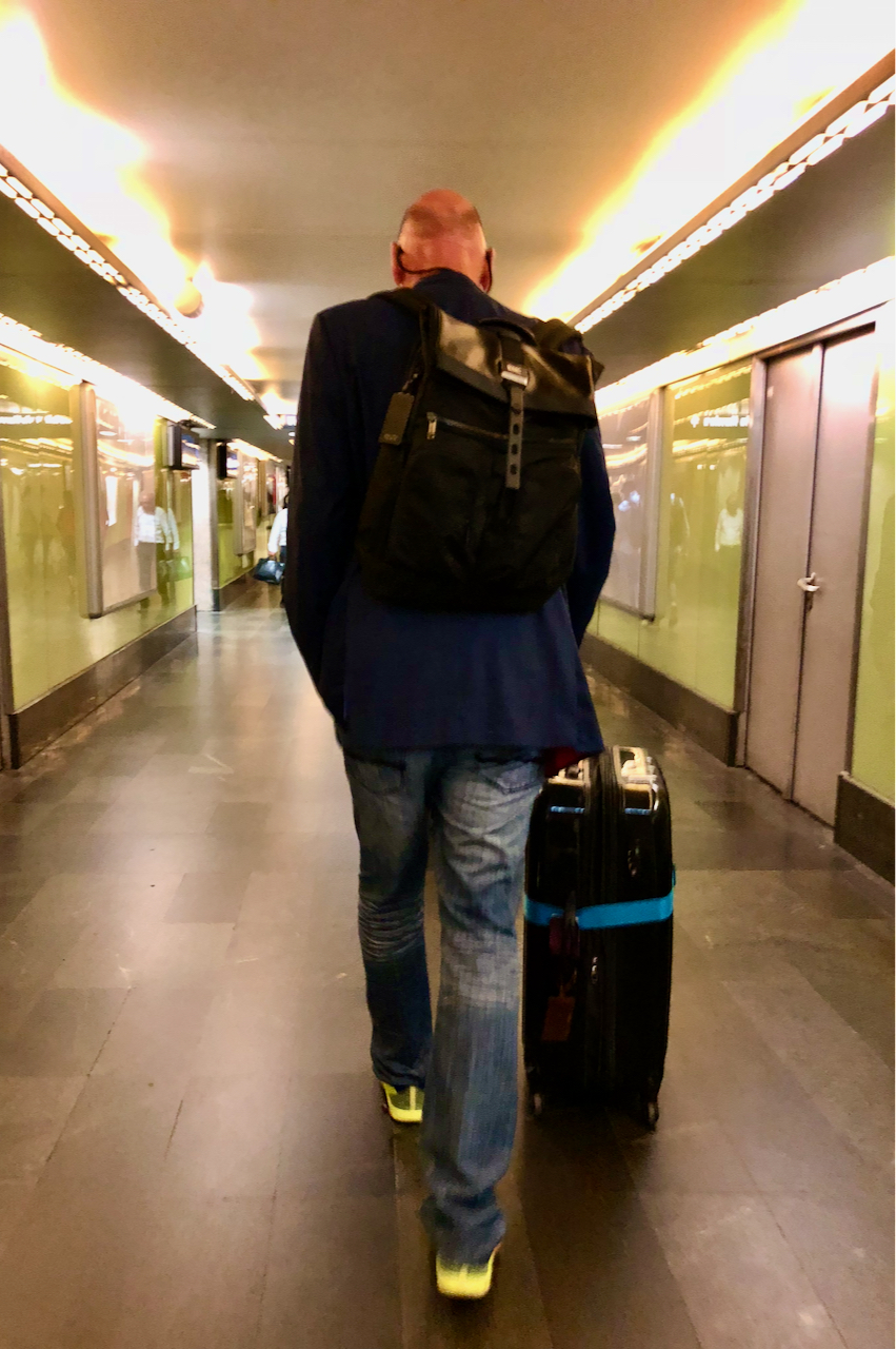 A tall man walking down a hall with a low ceiling.